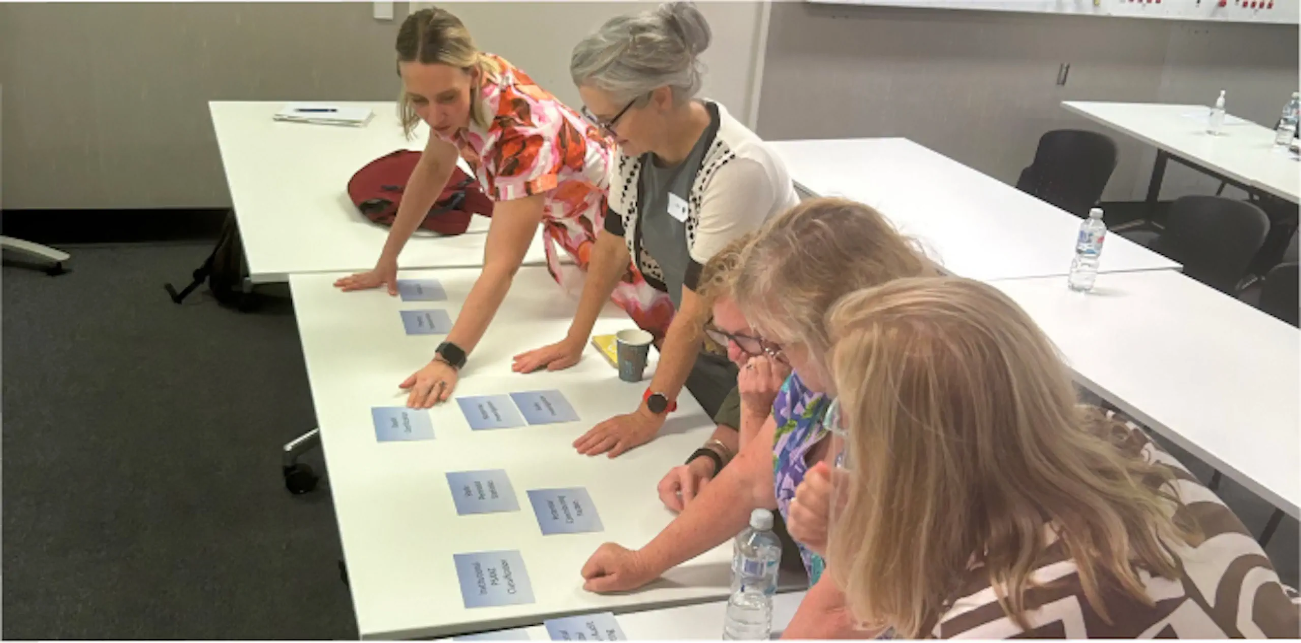 group of people standing around a table with sticky notes